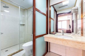 Une salle de bain moderne avec une douche à parois de verre, des toilettes et un lavabo surmonté d’un miroir.