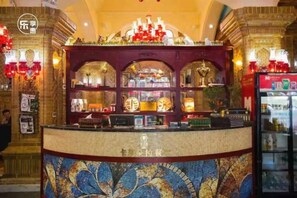 A reception area with a counter, a decorative wall, and a refrigerator. - New Saitun Hotel (Yiwu)