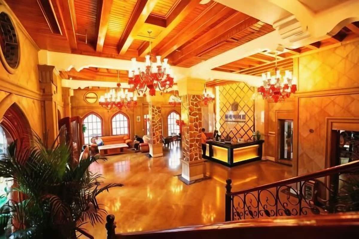 Un hall d’entrée spacieux avec un plafond haut, des lustres et un comptoir d’accueil.