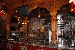 Eine Bar mit einer Marmorplatte, einer Kaffeemaschine und einem an der Wand befestigten Fernseher.
