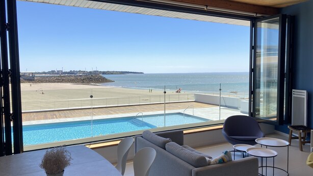 Ein modernes Zimmer mit großem Fenster, Blick auf Strand und Pool.