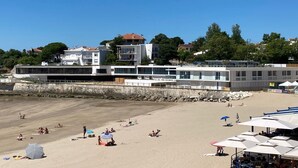 Ein Hotel am Strand mit moderner Architektur, einem Sandstrand und Sonnenschirmen.