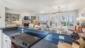 A spacious kitchen with a large island, built-in shelves, and a view to the outside.