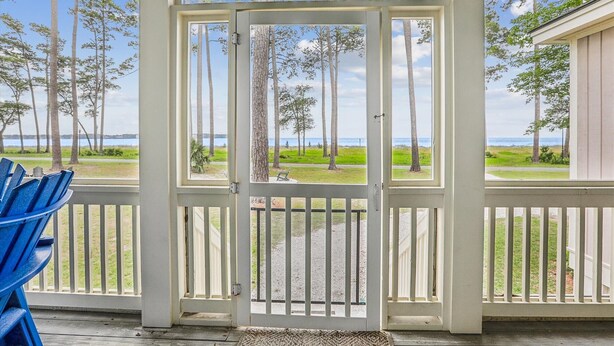 A covered porch with a view of the ocean and trees.
