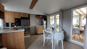 Una cocina moderna con armarios de madera, horno empotrado y comedor con mesa y sillas blancas.