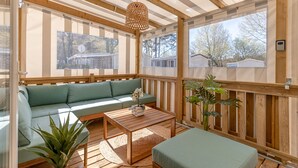Una terraza de madera con un sofá, una mesa y una lámpara colgante.