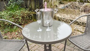 A round glass table with a metal bucket containing a bottle and two glasses. - 1 bedroom accommodation in Sway, near Lymington (Sway, near Lymington)