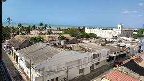Uma vila costeira com edifícios brancos, uma praia e palmeiras.
