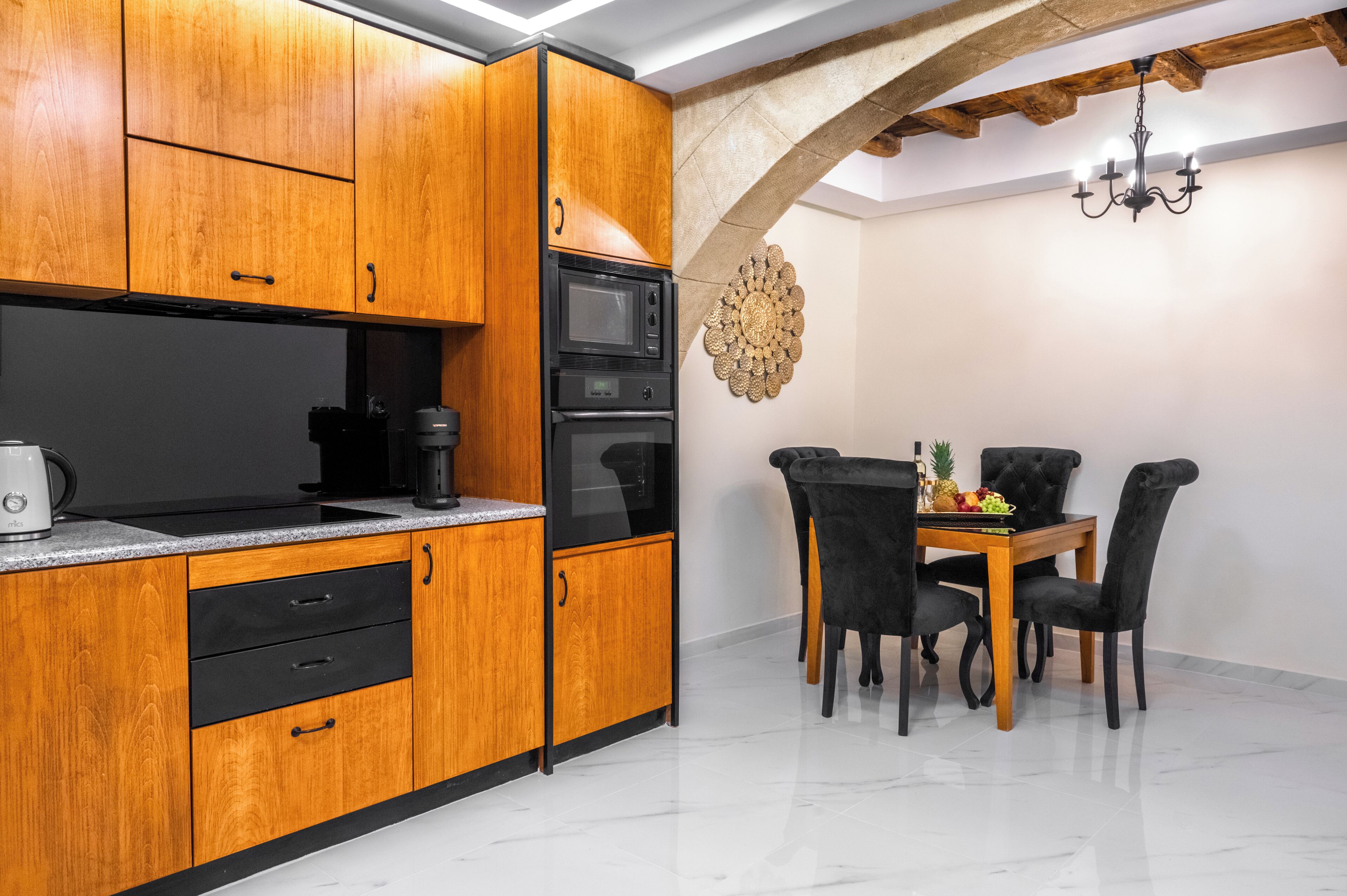 A modern kitchen with wooden cabinets, a built-in microwave, and a dining area with a table and chairs.