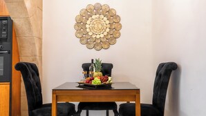 Een eetruimte met een houten tafel, zwarte stoelen met bekleding, een kroonluchter en een decoratief wandobject.
