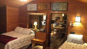 Um quarto acolhedor em estilo cabana, com duas camas, uma mesa pequena e um espaço de cozinha compacta.