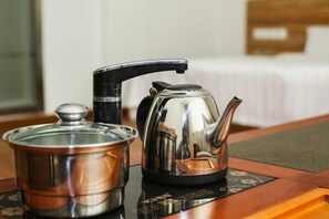 A stainless steel kettle and a pot on a wooden table with a placemat. - Shangjia Hotel (Anping)