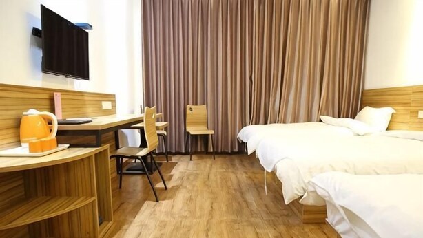 Habitación de hotel con escritorio de madera, una silla, una cama y televisión montada en la pared.