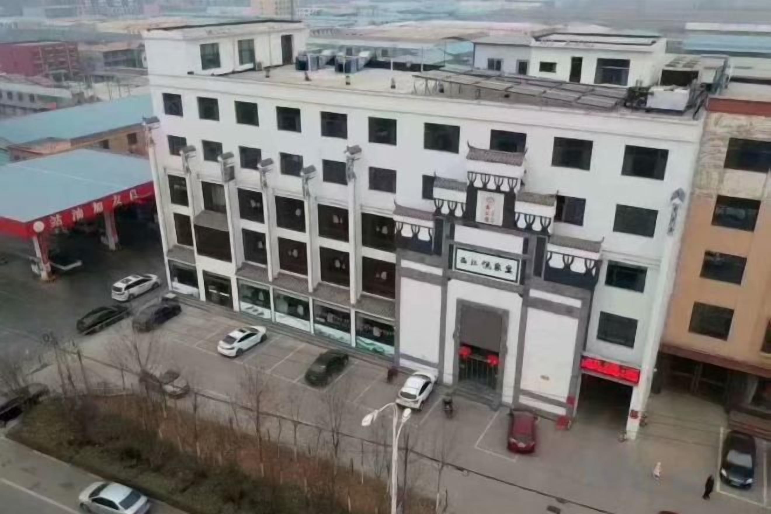 Um edifício de vários andares com entrada central, estacionamento e várias janelas.