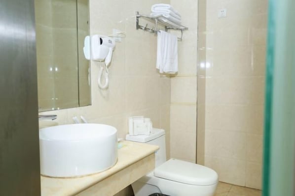 A bathroom with a sink, toilet, and a hairdryer on the wall.