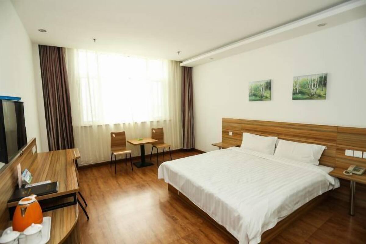 A hotel room with a bed, a desk, a chair, and a television.
