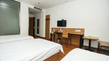 A hotel room with two beds, a desk, a chair, a television, and a small table.