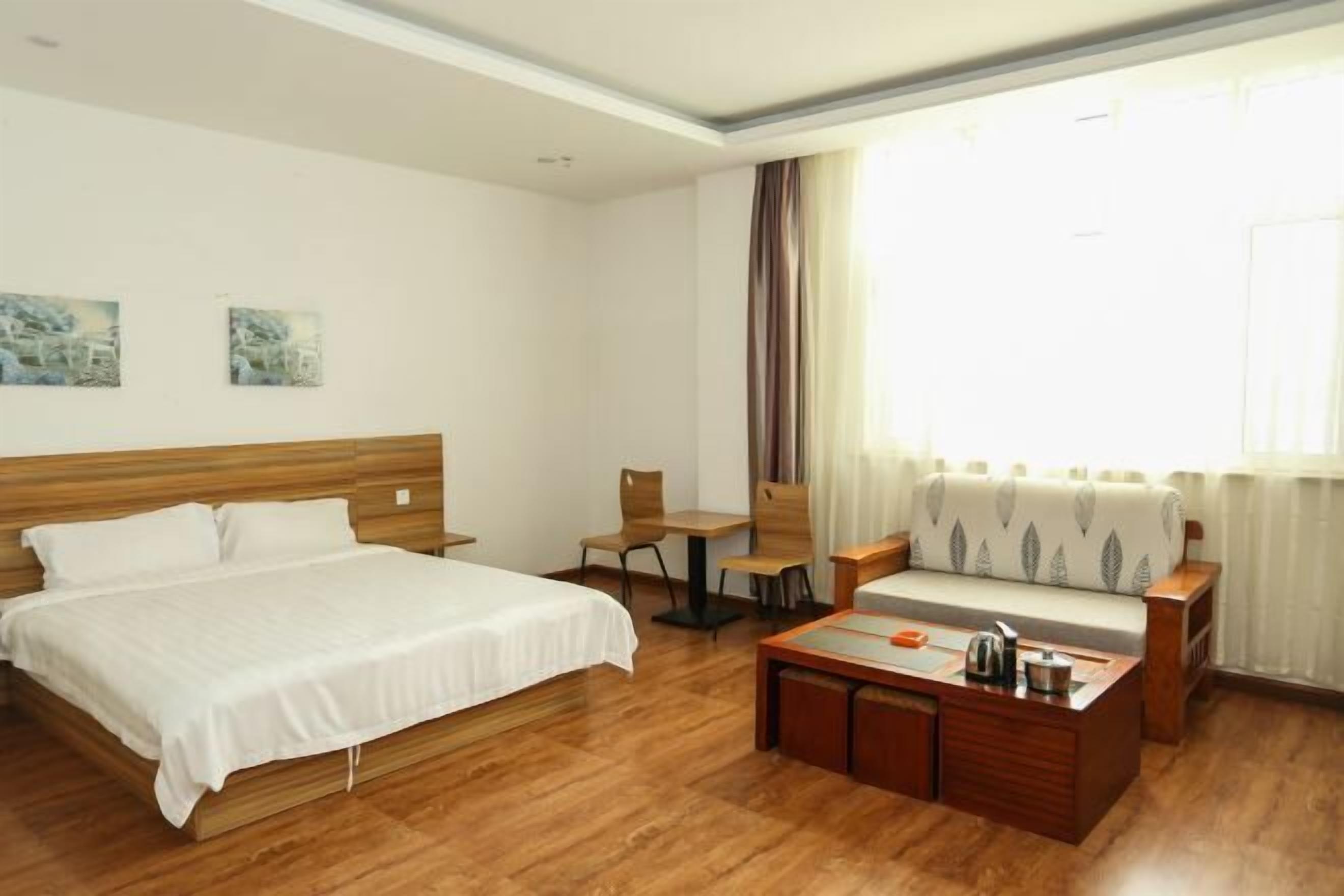 Une chambre d’hôtel avec un lit, un canapé, une petite table et une fenêtre avec des rideaux.