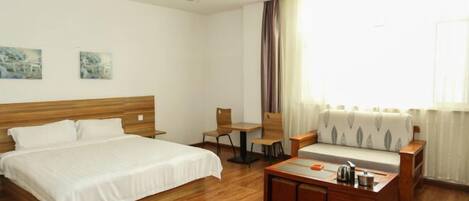 Une chambre d’hôtel avec un lit, un canapé, une petite table et une fenêtre avec des rideaux.