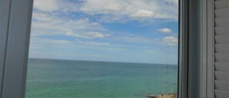 A view of the ocean through a window with a clear sky and a few clouds.