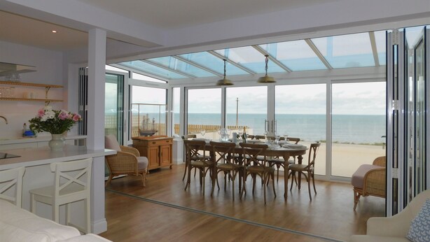 Un'ampia stanza con una grande zona pranzo, una cucina e vista sul mare.