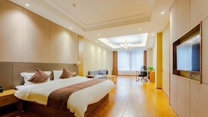 Ein modernes Hotelzimmer mit einem großen Bett, einem Schreibtisch, einem Sessel und einem Fernseher.
