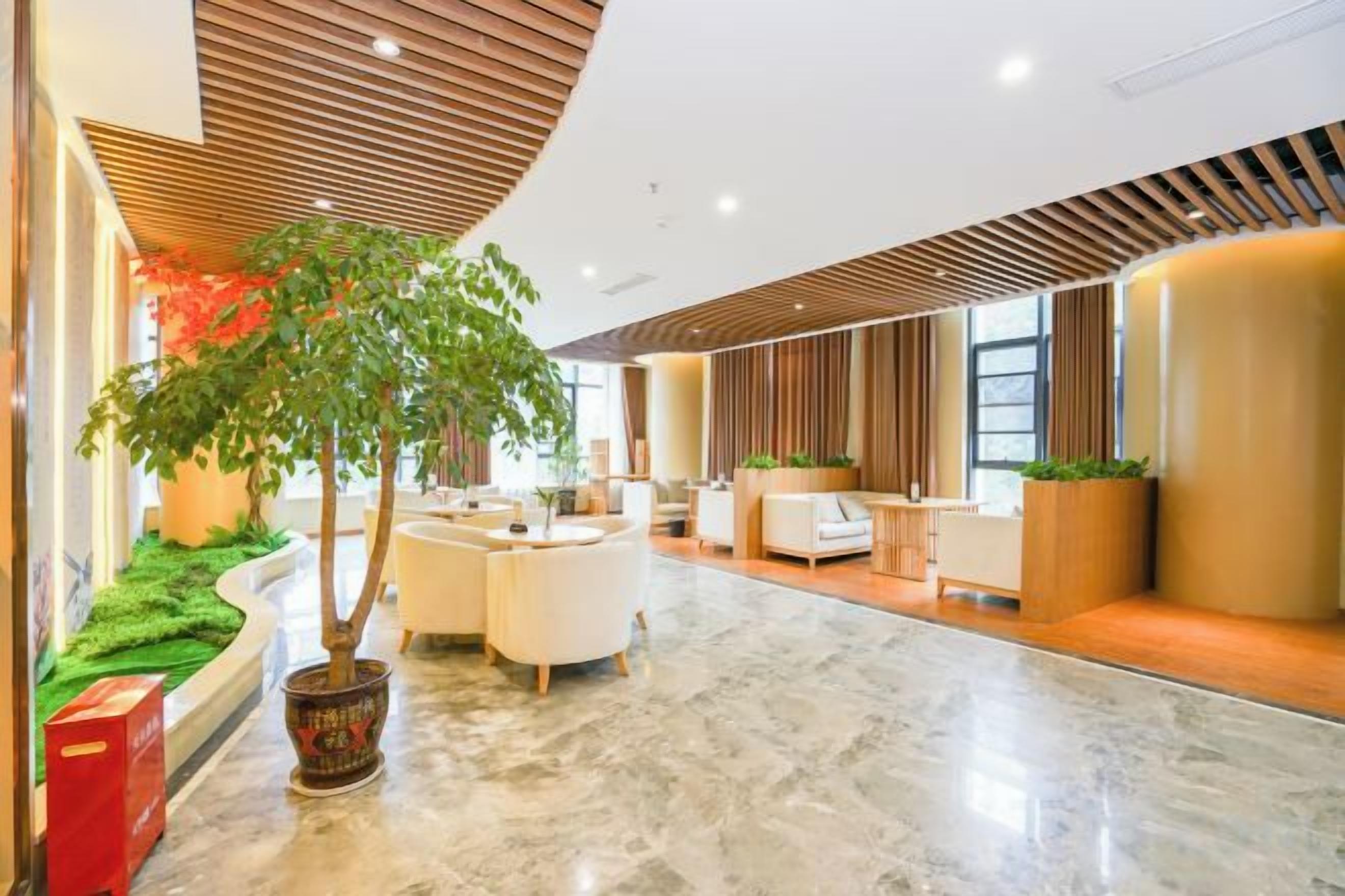 A hotel lobby with a curved ceiling, seating area, and a large potted plant.