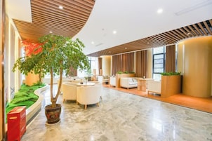 Vestíbulo de hotel con techo curvo, zona de estar y una planta grande en maceta.