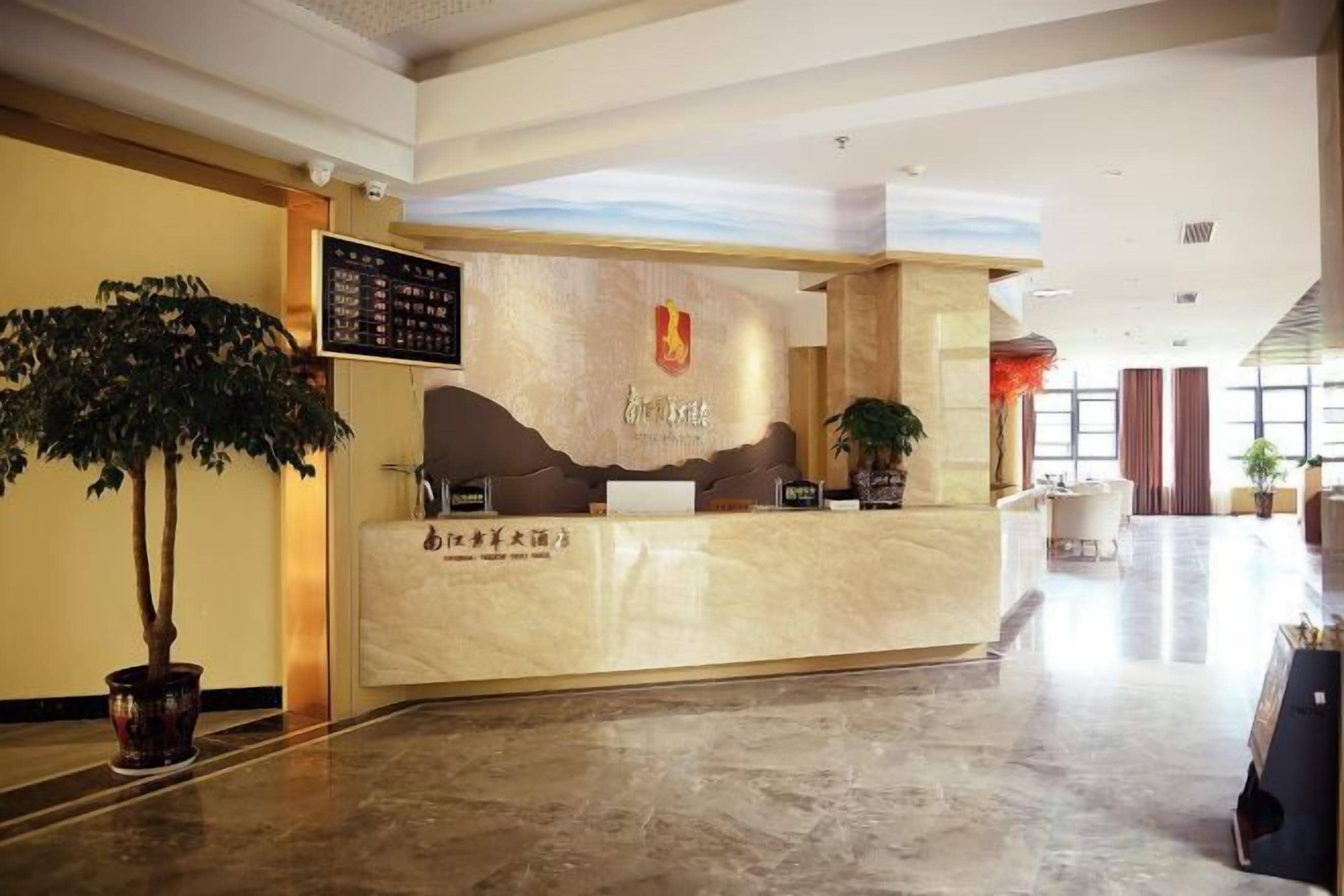 A hotel reception area with a marble counter, a potted plant, and a wall-mounted menu board.
