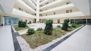 Ein mehrgeschossiges Atrium mit einem zentralen Gartenbereich und einer Glasfassade.