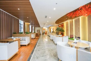 Un vestíbulo de hotel con zonas de estar, un mostrador de recepción y un área de recepción.