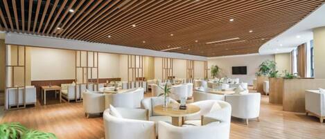 A spacious hotel lobby with multiple seating areas, a wooden ceiling, and a reception desk.