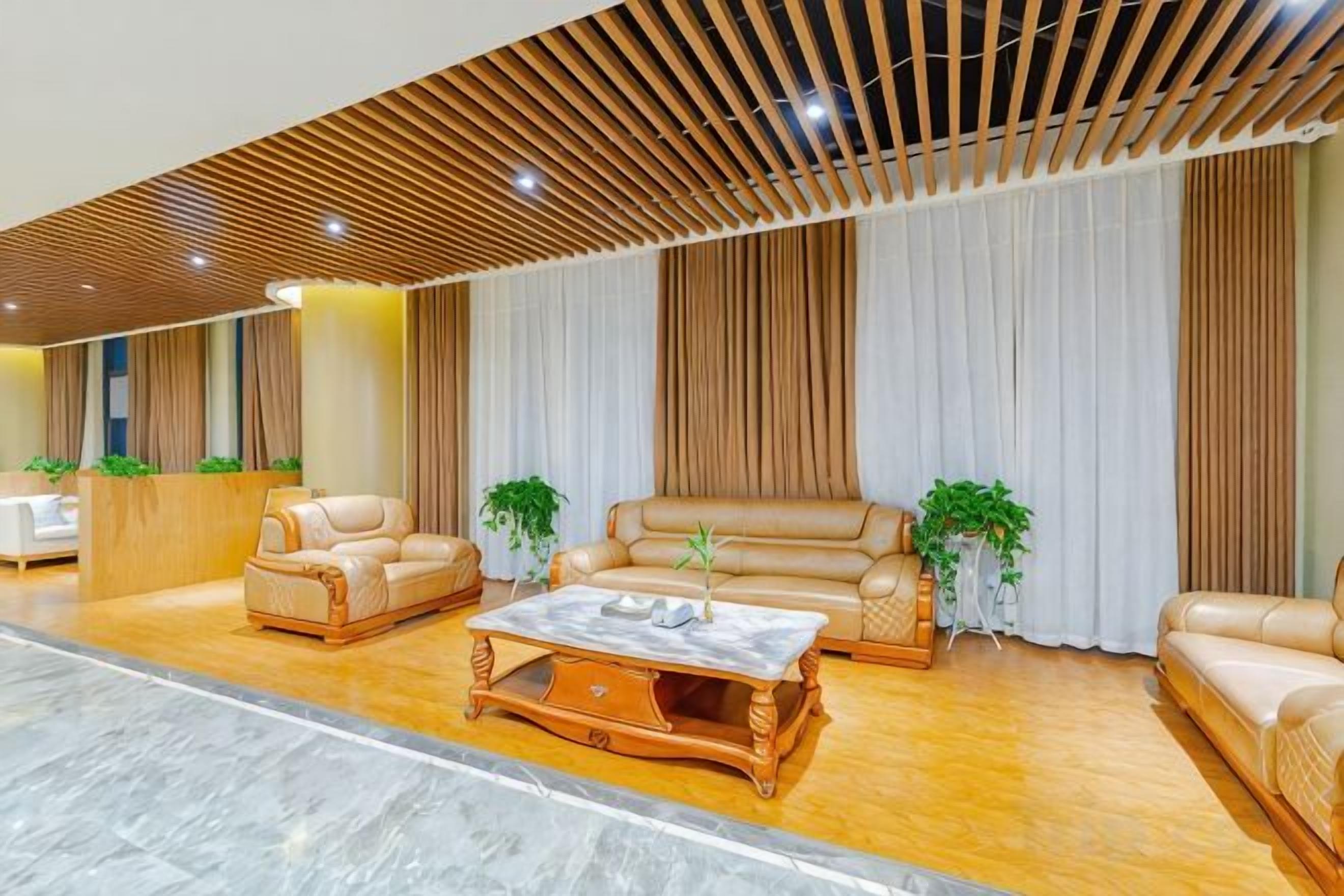 A spacious lobby with leather sofas, a marble coffee table, and a reception desk.