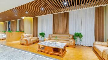 A spacious lobby with leather sofas, a marble coffee table, and a reception desk.