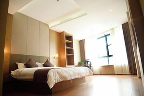 A modern hotel room with a large bed, built-in shelving, a desk, and a large window. - Huangyang Hotel (Nanjiang Dejian) (Nanjiang)