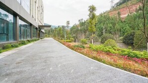 Un vialetto che conduce a un edificio dal design moderno, immerso nel verde e alberi.