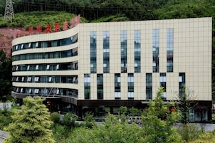 Un edificio de varios pisos con un diseño arquitectónico moderno, que presenta una serie de ventanas y un techo plano.
