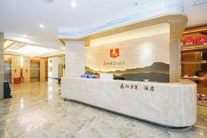 A reception desk with a logo, a sign with text, and a marble floor. - Huangyang Hotel (Nanjiang Dejian) (Nanjiang)
