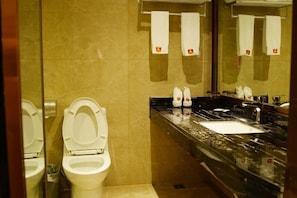 A bathroom with two toilets, a sink, and a mirror. - Huangyang Hotel (Nanjiang Dejian) (Nanjiang)