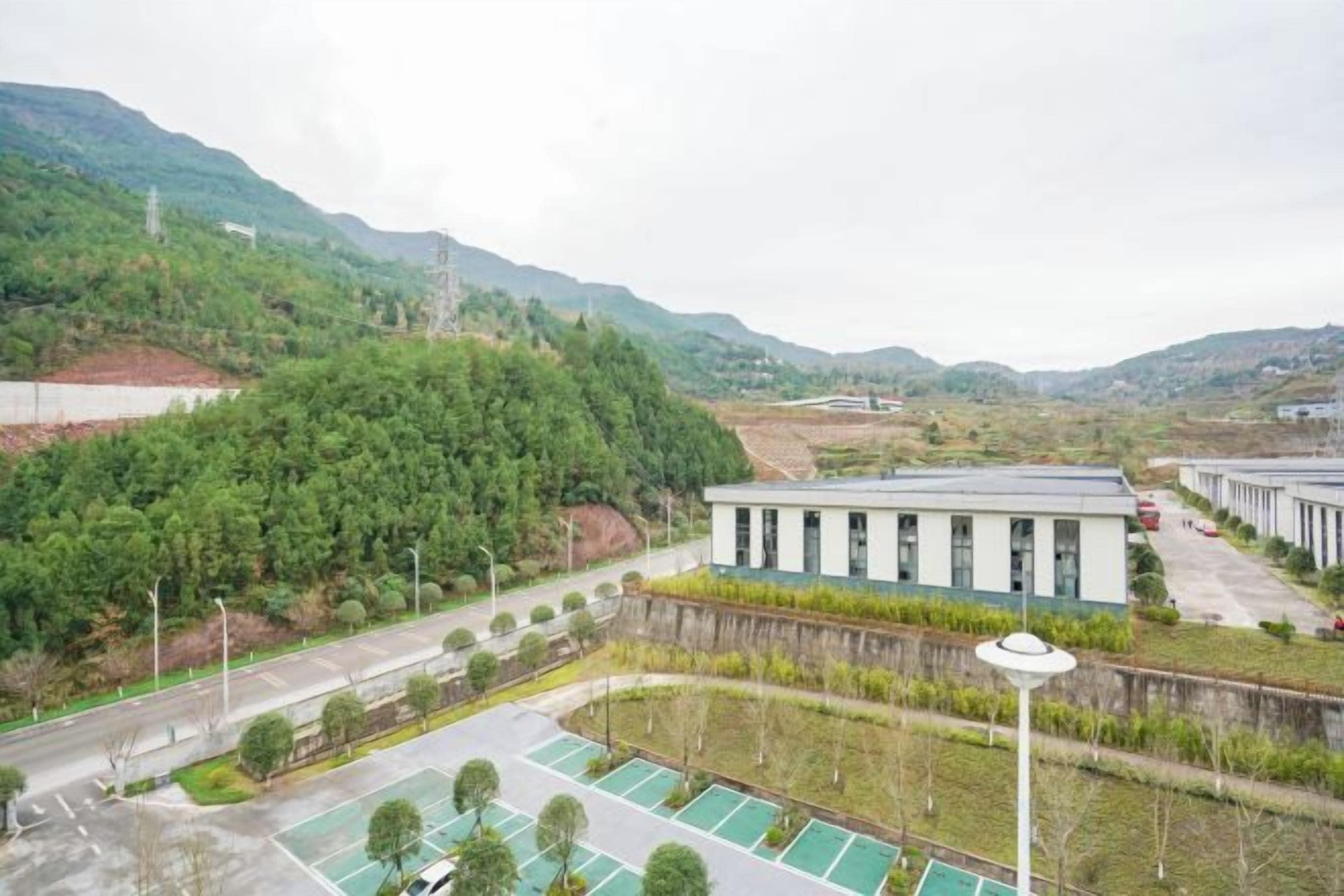 A building with a modern design, surrounded by a parking area and greenery.
