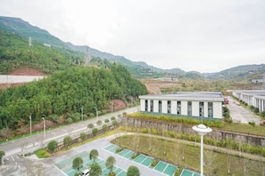 A building with a modern design, surrounded by a parking area and greenery. - Huangyang Hotel (Nanjiang Dejian) (Nanjiang)