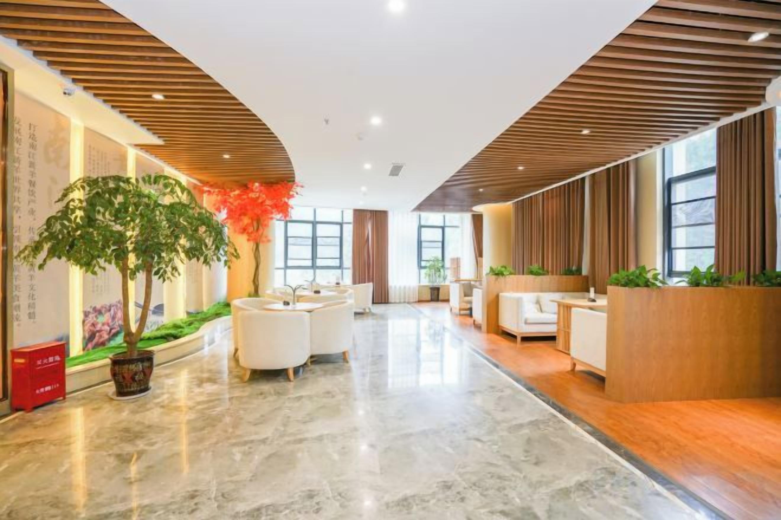Un moderno vestíbulo de hotel con recepción, zona de estar y una planta grande en maceta.