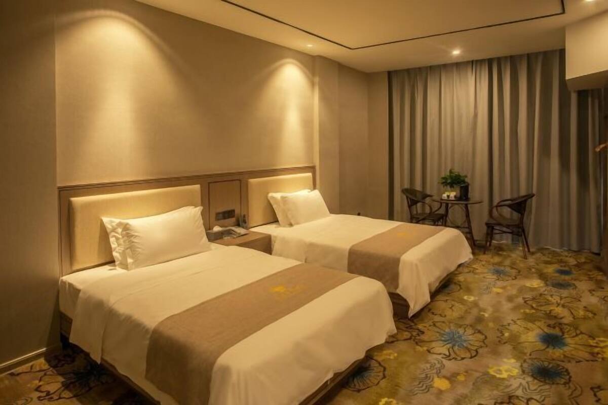A hotel room with two beds, a small table with chairs, and a curtain.