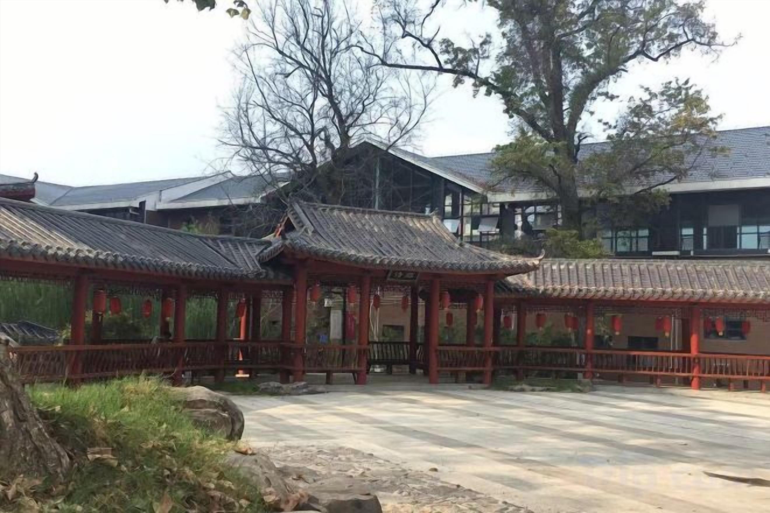 A traditional building with a tiled roof and wooden structure, surrounded by a paved courtyard.
