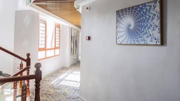 A hallway with a wooden staircase, patterned floor, and a framed artwork on the wall.