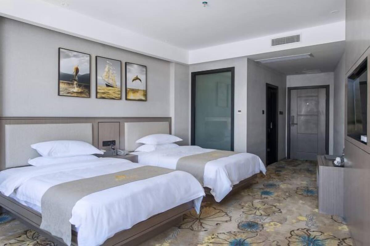 A hotel room with two beds, a desk, and a door.