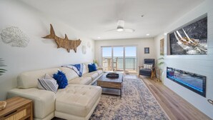 A spacious living room with a large window, a ceiling fan, and a view of the ocean.