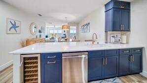 A modern kitchen with a large island, dark blue cabinets, and stainless steel appliances.