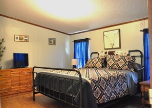 A bedroom with a metal bed frame, a wooden dresser, and a television on a stand.