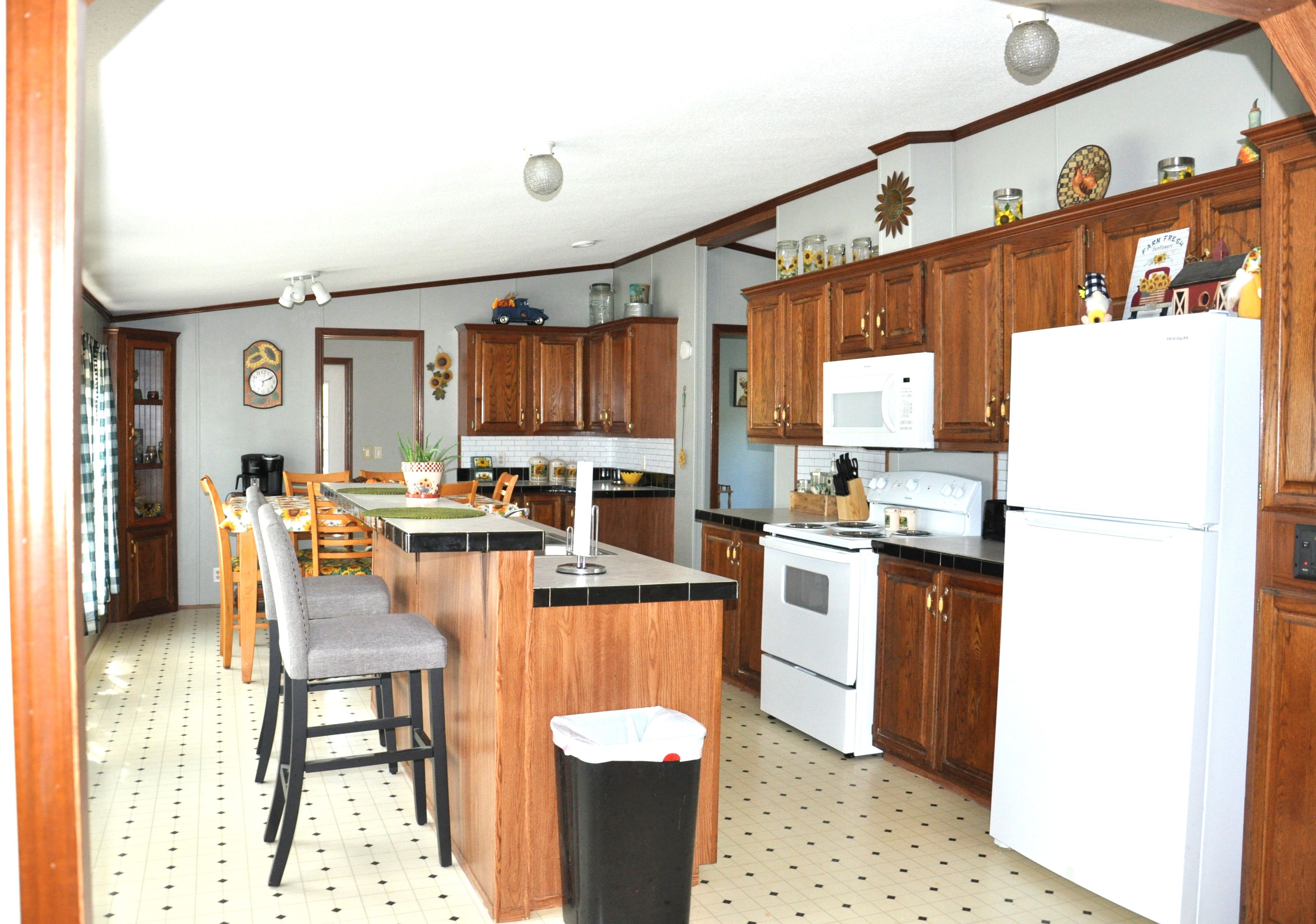 A kitchen with wooden cabinets, a central island, a microwave, and a refrigerator.